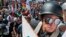 A white nationalist demonstrator with a helmet and shield walks into Lee Park in Charlottesville, Va., Aug. 12, 2017. Hundreds of people chanted, threw punches, hurled water bottles and unleashed chemical sprays on each other Saturday after violence erupted at a white nationalist rally in Virginia. 