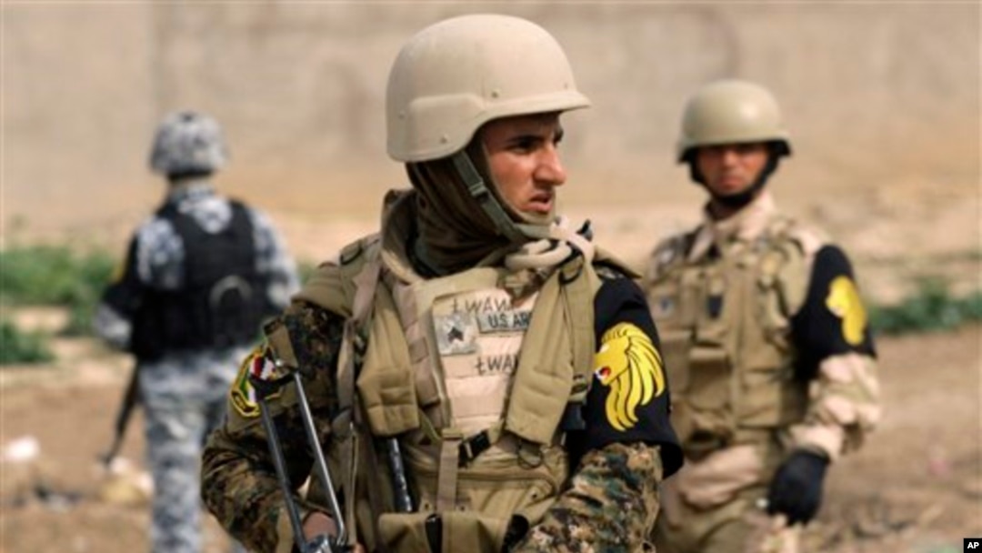 Một chiến binh người Kurd (giữa) đứng gác cùng một cảnh sát Iraq (trái) và một binh sĩ quân đội Iraq ở ngoại ô Kirkuk, phía bắc Baghdad, Iraq.