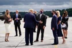 El presidente Donald Trump saluda al gobernador de Georgia, Brian Kemp y su esposa Marty, junto al senador republicano David Perdue, de Georgia, al llegar a la Base Dobbins de la Reserva Aérea, en Atlanta, para un evento electoral. Sep. 25 de 2020.