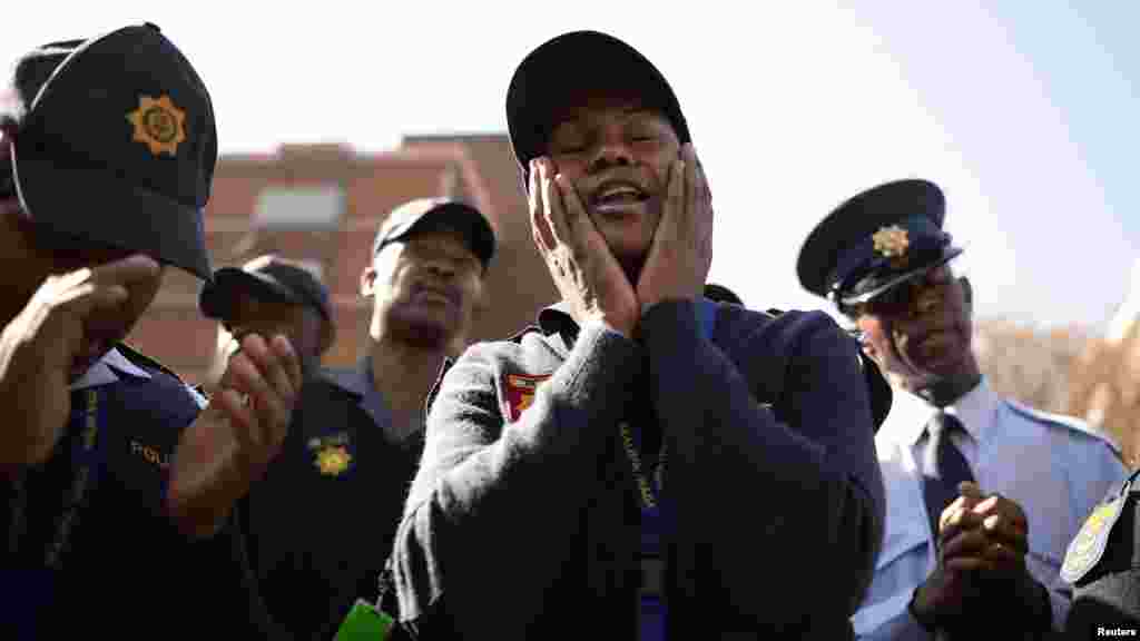 Police Constable Maureen Mailula prays with colleagues of the National Protection Unit for ailing former South African President Nelson Mandela.