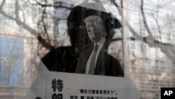 A man reading a newspaper posted on a public bulletin board is reflected in the glass, in Beijing, Jan. 3, 2017. The photo of U.S. President-elect Donald Trump is published with an article that reads "Trump uses fist to talk."
