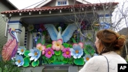 FILE - Designer Caroline Thomas looks at a house decorated like a parade float in New Orleans, Jan. 8, 2021. Thousands of houses are being decorated as floats because the coronavirus pandemic has canceled Mardi Gras parades.