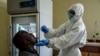 FILE - A Ugandan health worker takes samples to test a truck driver for the coronavirus, at the Malaba Border Post in Malaba, Uganda, April 29, 2020.