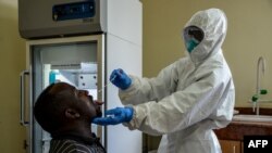 Un agent de la santé ougandais prélève des échantillons pour tester le coronavirus chez un chauffeur de camion, au poste frontière de Malaba, à la frontière avec le Kenya, en Ouganda, le 29 avril 2020.