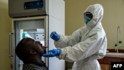 FILE - A Ugandan health worker takes samples to test a truck driver for the coronavirus, at the Malaba Border Post in Malaba, Uganda, April 29, 2020.