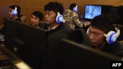 FILE - Young men sit at computers at an internet cafe in Beijing, China, Dec. 16, 2015.