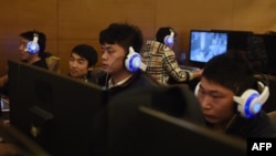 FILE - Young men sit at computers at an internet cafe in Beijing, China, Dec. 16, 2015.