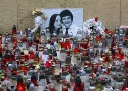 FILE - Candles are seen in front of a photo of journalist Jan Kuciak and his fiancee Martina Kusnirova, in Bratislava, Slovakia, March 9, 2018.
