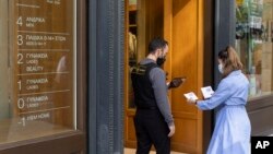 A woman is checked for her Covid-19 vaccination certificate in order to be allowed to enter a shop in Athens, Greece, Nov. 6, 2021. 