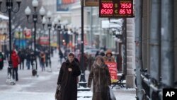 Women pass a currency exchange kiosk on a street in Moscow, Russia, Jan. 18, 2016. The Russian ruble, battered by weak oil prices, on Monday dropped to new lows and broke an all-time record against the euro.