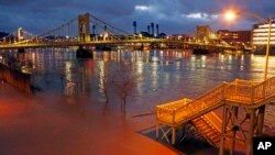 Steps to the Ninth Street bridge and Duquesne Boulevard in downtown Pittsburgh are flooded as the Allegheny River overflows its banks Feb. 16, 2018. A band of thunderstorms is bringing more rain into parts of the country already under high water.