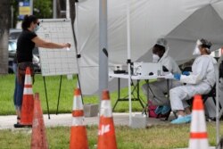 Health care workers take information from people in line at a walk-up COVID-19 testing site during the coronavirus pandemic, in Miami Beach, Fla., July 17, 2020.