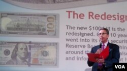 Pejabat Bank Sentral Amerika, Michael Lambert memperkenalkan desain baru uang kertas 100 dolar Amerika di @America, Jakarta, 23 Oktober 2013 (VOA/Iris Gera).