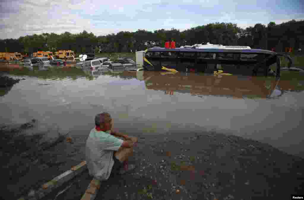 A man waits next to a flooded highway after his car was trapped following heavy rainfalls in Fangshan District, Beijing, China, July 22, 2012.