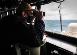 El alférez Grayson Sigler de Corpus Christi, Texas, observa mientras el USS John S. McCain realiza operaciones en el Estrecho de Taiwán, el 30 de diciembre de 2020.