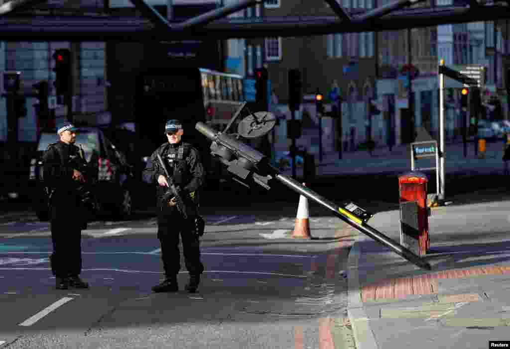 Armed police officers stand near the site where attackers crashed their van after running over pedestrians on London Bridge, next to Borough Market in central London, June 5, 2017.