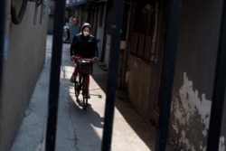 A woman wears a face mask as she rides a bicycle in a street in Beijing as the country is hit by an outbreak of the novel coronavirus, China, February 26, 2020.