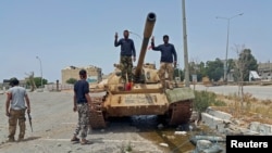 Members of Libya's pro-government forces gesture as they stand on a tank in Benghazi, Libya, May 21, 2015.