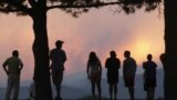 People watch a giant smoke plume rising from the Waldo Canyon Fire during sunset, west of Colorado Springs