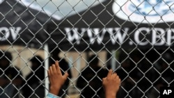 A migrant leans on a fence of the Gateway International Bridge that connects Matamoros, Mexico, with Brownsville, Texas, Oct. 10, 2019. Some Central American asylum-seekers have been sent to Hawaii to await their court date.