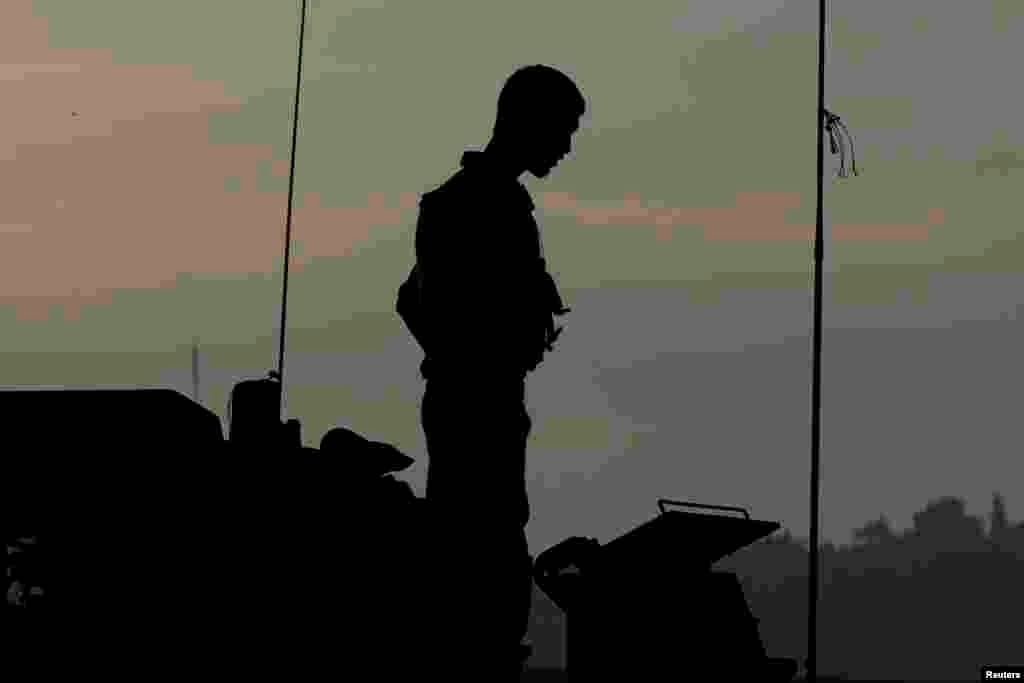 An Israeli soldier stands atop an armored vehicle at a staging area near the border with the Gaza Strip July 31, 2014.