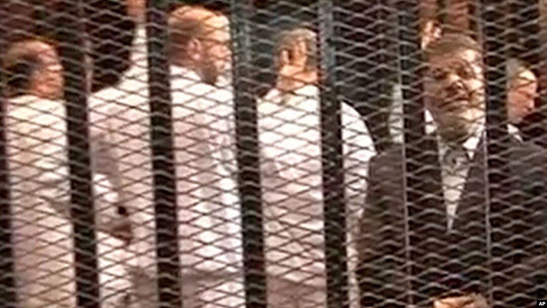 FILE - A Nov. 2013 image made from video provided by Egypt's Interior Ministry shows ousted President Mohammed Morsi (R), speaking from the defendant's cage during a trial hearing in Cairo, Egypt.