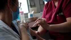 A member of the medical staff administers the Oxford-AstraZeneca COVID-19 vaccine to a colleague at the Foch hospital in Suresnes, near Paris, France, Feb. 8, 2021.