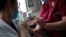 A member of the medical staff administers the Oxford-AstraZeneca COVID-19 vaccine to a colleague at the Foch hospital in Suresnes, near Paris, France, Feb. 8, 2021. 