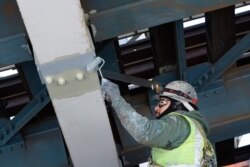 A painter works on steel support beams underneath the Manhattan Bridge, part of New York's aging infrastructure, April 6, 2021.