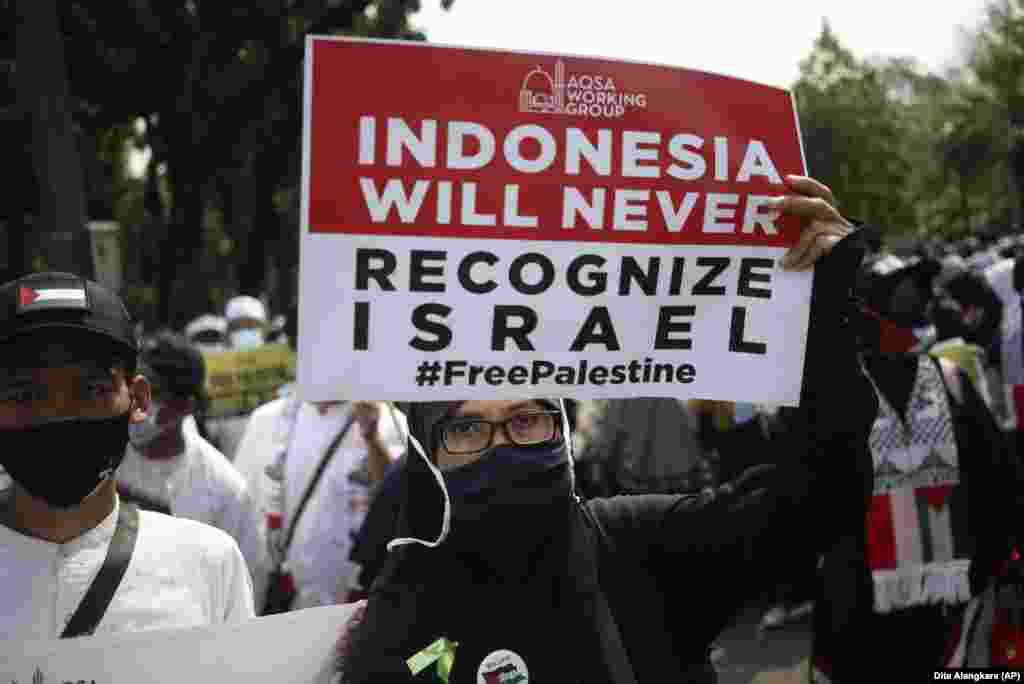 Seorang perempuan Muslim memegang poster saat aksi unjuk rasa untuk menentang serangan Israel di Gaza, di luar Kedutaan Besar AS di Jakarta, hari Jumat, 21 Mei 2021. (Foto: Dita Alangkara / AP)