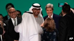 FILE - United Nations Climate Chief Simon Stiell, from left, COP28 President Sultan al-Jaber and John Kerry, U.S. Special Presidential Envoy for Climate, pose for photos at the end of the COP28 U.N. Climate Summit, Wednesday, Dec. 13, 2023, in Dubai, United Arab Emirates.