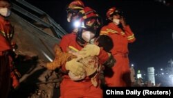 A worker wearing a face mask rescues a child at the site where a hotel being used for the coronavirus quarantine collapsed, in the southeast Chinese port city of Quanzhou, Fujian province.