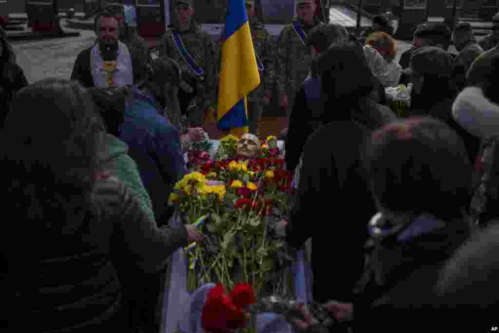 Personas se despiden y colocan flores en el ataúd del militar ucraniano caído, Vadym Popelniuk, durante un servicio religioso en la Plaza de la Independencia en Kiev, Ucrania, el 5 de abril de 2024. (Foto AP/Vadim Ghirda)