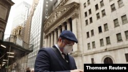 Un hombre usa una máscara protectora mientras camina por Wall Street en Nueva York.