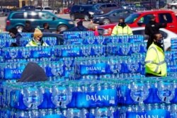Water is loaded into cars at a distribution site, Feb. 19, 2021, in Houston. The drive-through stadium location was set up to provide bottled water to individuals who needed water while the city remains on a boil notice.
