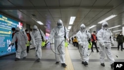 Workers wearing protective gear disinfect as a precaution against the new coronavirus at the subway station in Seoul, South Korea, March 11, 2020. 