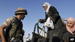 Un soldado jordano ayuda a refugiados sirios que cruzan la frontera.