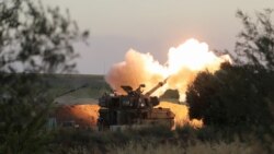 Israeli soldiers work in an artillery unit as it fires near the border between Israel and the Gaza strip, on the Israeli side May 19, 2021.