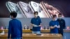 Empleados de una tienda Apple en China usan mascarillas para atender a los clientes. Las fábricas de iPhone en China van retrasadas lo cual desestabiliza los planes de Apple. (Foto Reuters)