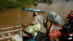 រូបឯកសារ៖ អាជីវករ​ម្នាក់ ជិះ​លើ​សាឡាង​ដោយ​មាន​ដឹក​ទំនិញ​របស់​ខ្លួន​លើ​ម៉ូតូ ពេល​ឆ្លង​ទន្លេ​មេគង្គ​នៅ​ជាយ​រាជធានី​ភ្នំពេញ នៃ​ប្រទេស​កម្ពុជា កាលពី​ថ្ងៃពុធ ទី២២ ខែកក្កដា ឆ្នាំ២០២០។