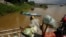 A vendor, foreground, stands on a ferry together with his goods before crossing the Mekong river in Dei Edth village at the outskirt of Phnom Penh, Cambodia, July 22, 2020. 