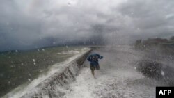 A resident walks past waves spilling over a wall onto a coastal road in the city of Legaspi in Albay province, south of Manila on December 14, 2015, as typhoon Melor approaches the city. 