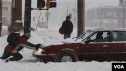 Seorang warga berusaha membantu pengendara mobil yang terjebak salju di kota St. Paul, Minnesota.