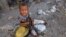 FILE - A girl displaced by the war in the northwestern areas of Yemen eats outside her family's makeshift hut on a street in the Red Sea port city of Hodeida, Yemen, Dec. 25, 2017.