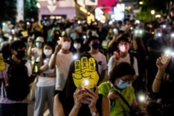 People hold up their phones with the light on in the Causeway Bay district of Hong Kong, June 4, 2021, after police closed the venue where Hong Kong people gather annually to mourn the victims of China's Tiananmen Square crackdown in 1989.