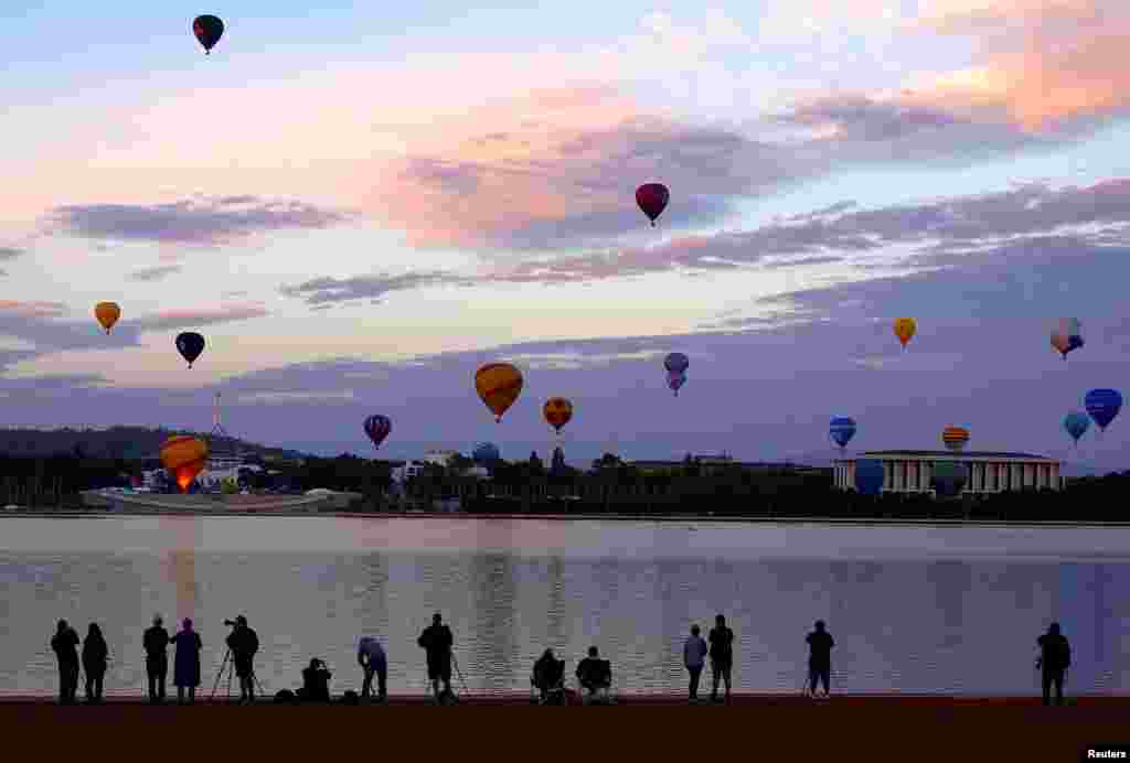 People watch as balloons fly above the Australian capital city during the Canberra Balloon Festival.