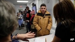 Helison Alvarenga, of Brazil, center, speaks with volunteers Marcia Previatti, front left, and Arlene Vilela, front right, at the New England Community Center, in Stoughton, Mass, Dec. 4, 2019. 