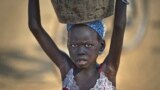 FILE - A young displaced girl carries a bucket of water back to her makeshift shelter at a United Nations compound which has become home to thousands of people displaced by the recent fighting, in the Jebel area on the outskirts of Juba, South Sudan, Dec. 31, 2013.