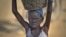FILE - A young displaced girl carries a bucket of water back to her makeshift shelter at a United Nations compound which has become home to thousands of people displaced by the recent fighting, in the Jebel area on the outskirts of Juba, South Sudan, Dec. 31, 2013.