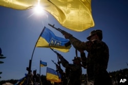 Honor guards shoot into the air during the funeral ceremony of six Ukrainian servicemen killed in a Russian rocket attack at a Ukrainian military academy, during their funeral ceremony in Poltava, Ukraine, Sept. 7, 2024.